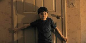 alex-standing-in-front-of-a-door-clutching-the-frame-with-a-terrified-expression-in-weapons.jpg